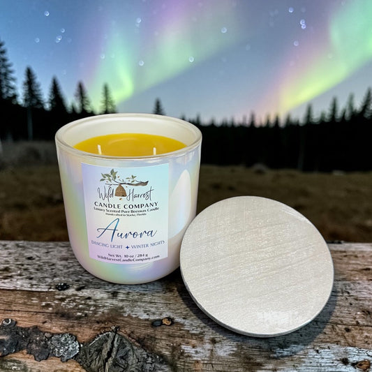 Aurora Candle with 'Wild Harvest Candle Company' label on a wooden surface with a Northern Lights background