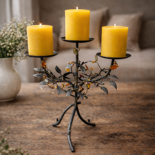 Decorative candle holder with three yellow candles on a wooden surface.