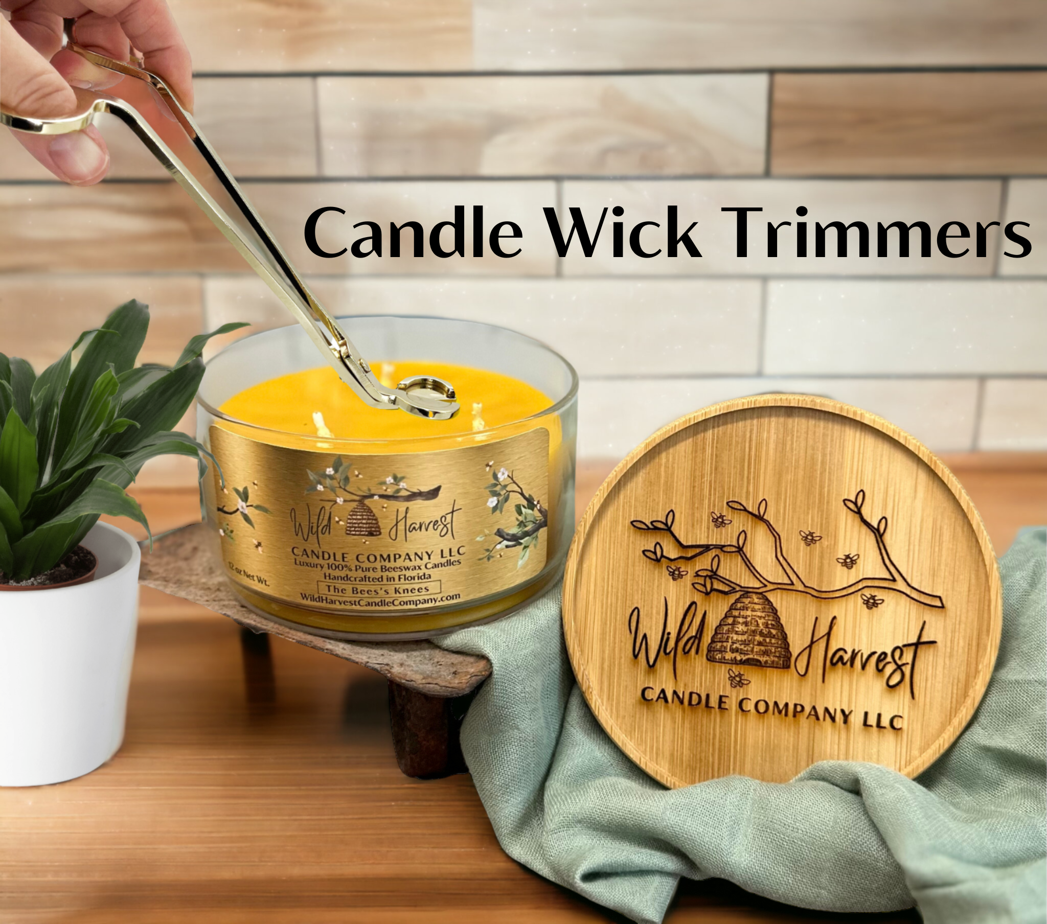 Candle wick trimmers being used on a candle with a wooden coaster and plant in the background by Wild Harvest Candle Company