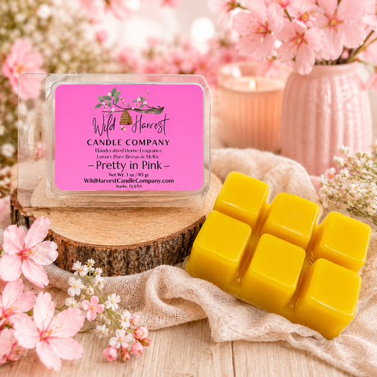 Yellow wax melts with a Wild Harvest Candle Company packaging on a wooden surface with pink flowers.