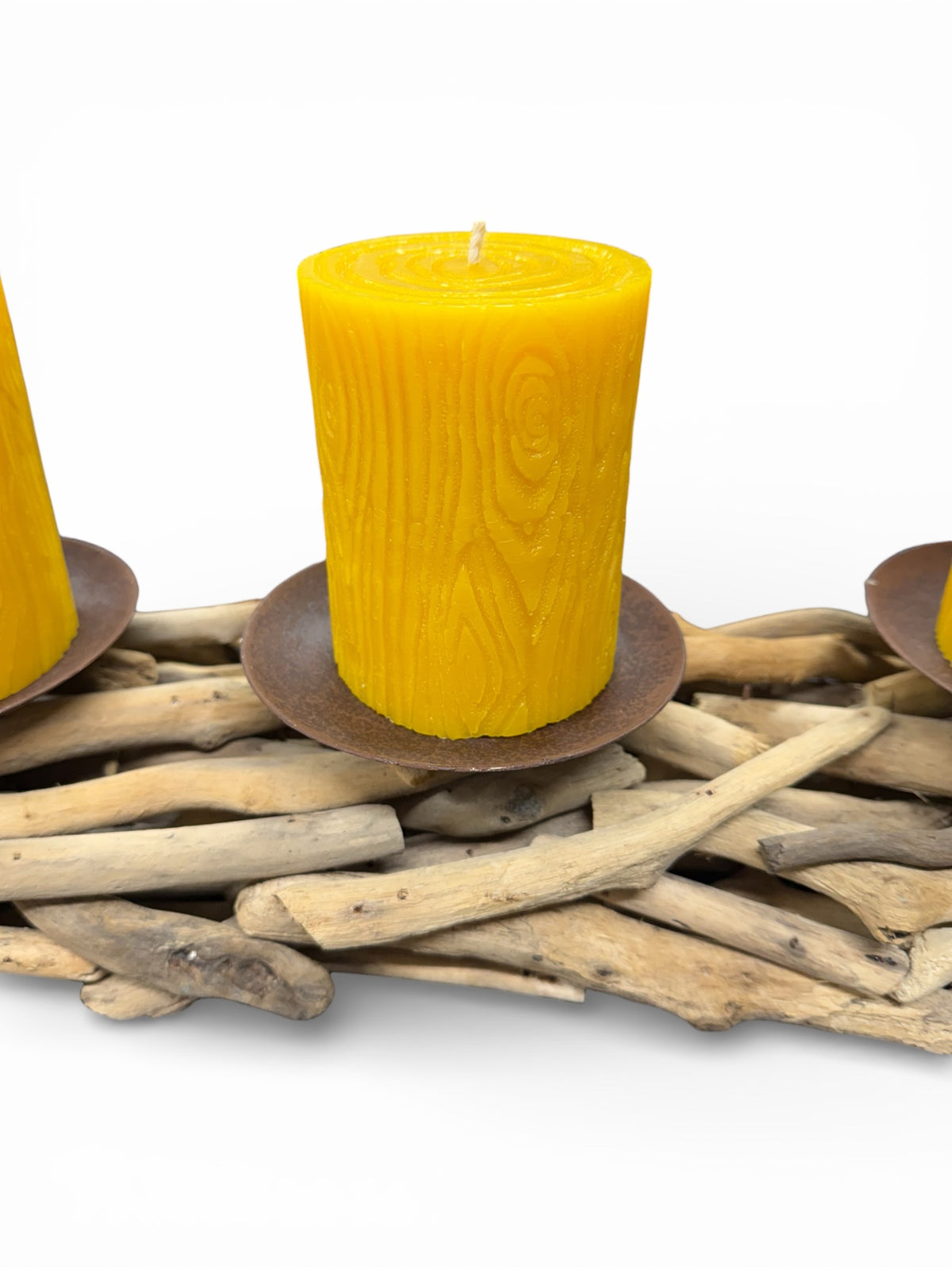 Yellow candles on a bed of driftwood with a white background